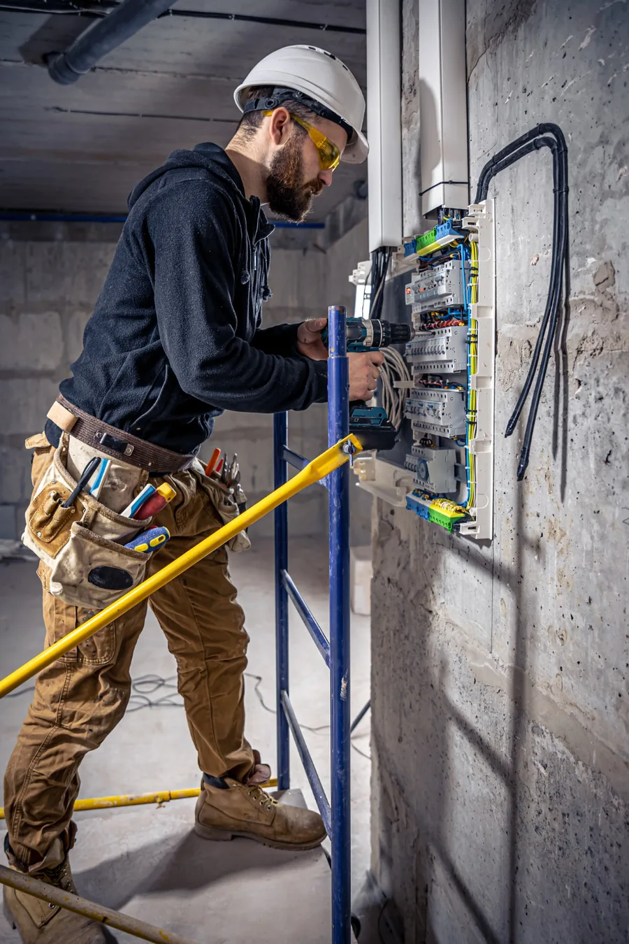 Electricista con casco instalando cableado en una pared
