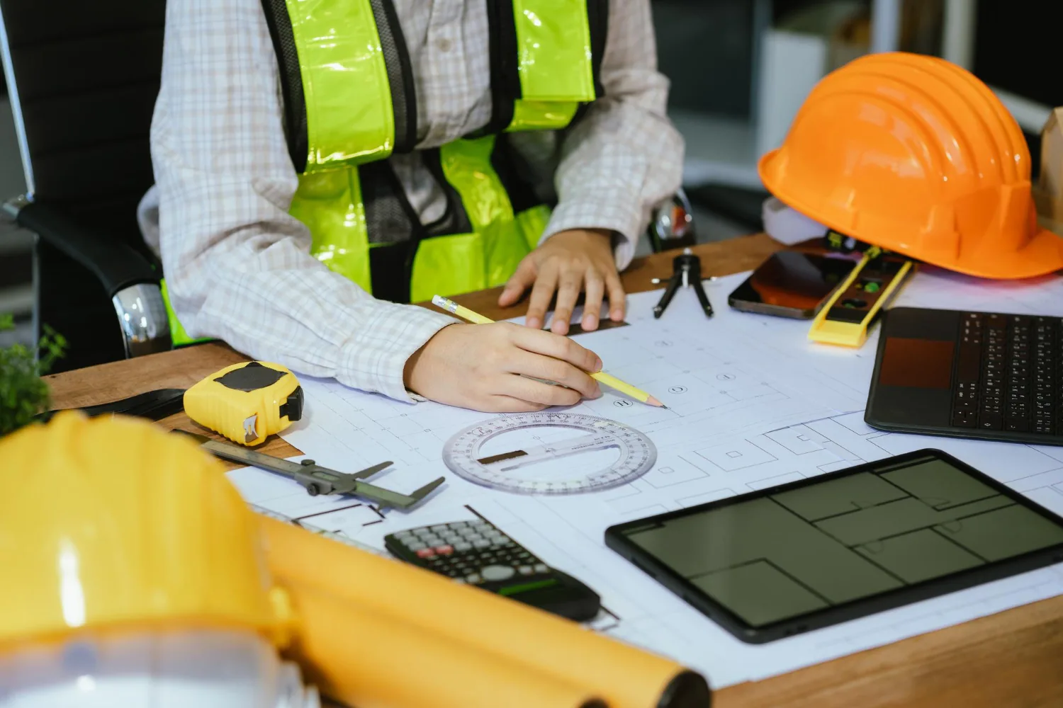 Escritorio con planos, casco, flexómetro y tableta de trabajo