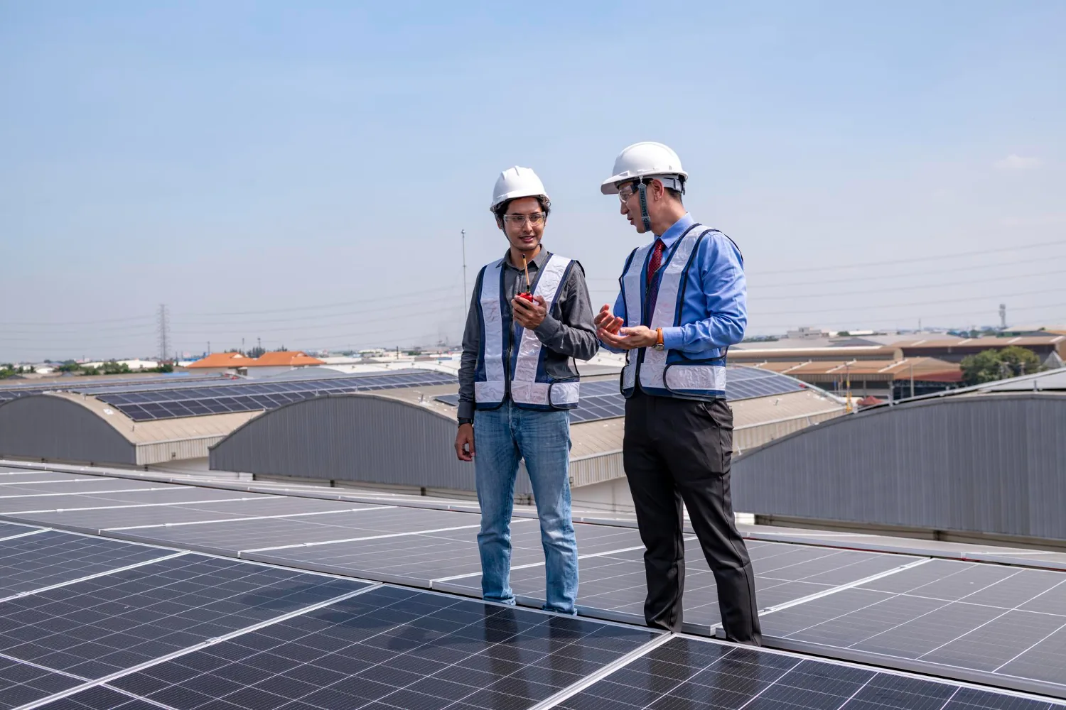 Dos profesionales de pie sobre un techo con paneles solares