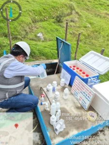 Profesional con casco tomando muestras de agua junto a un cooler