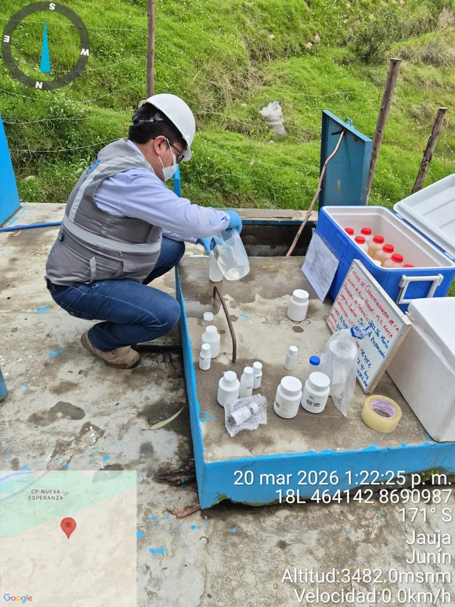 Profesional con casco tomando una muestra de agua en campo