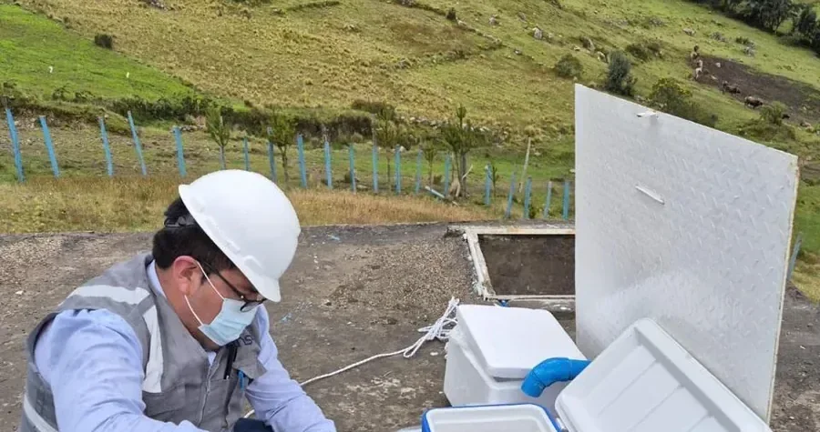Profesional con mascarilla y guantes trabajando junto a una hielera de muestras