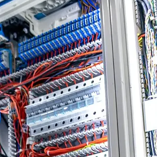Interior de un tablero eléctrico con interruptores y cableado de colores